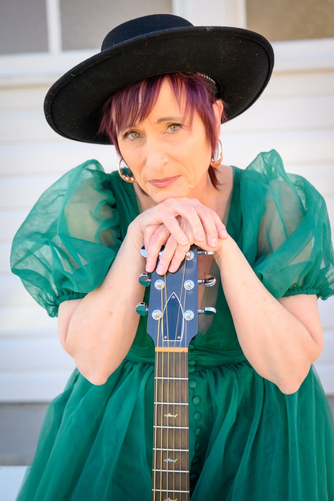 Randie O’Neil seated outdoors with her guitar
